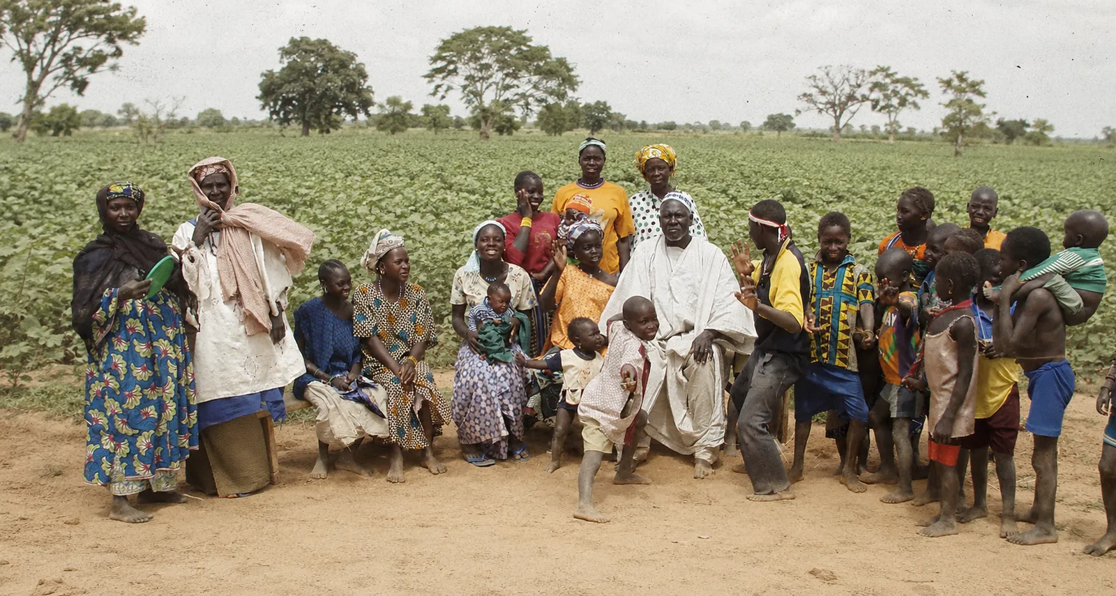 Grande famille africaine au village : le patriarche en boubou blanc entouré de ses épouses et de nombreux enfants